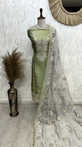 Green saree with silver embroidery on a mannequin against a white wall.