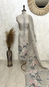 Gray embroidered dress with floral patterns on a mannequin against a white wall.