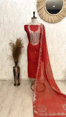 Red traditional outfit with white embroidery on a mannequin against a light-colored wall.