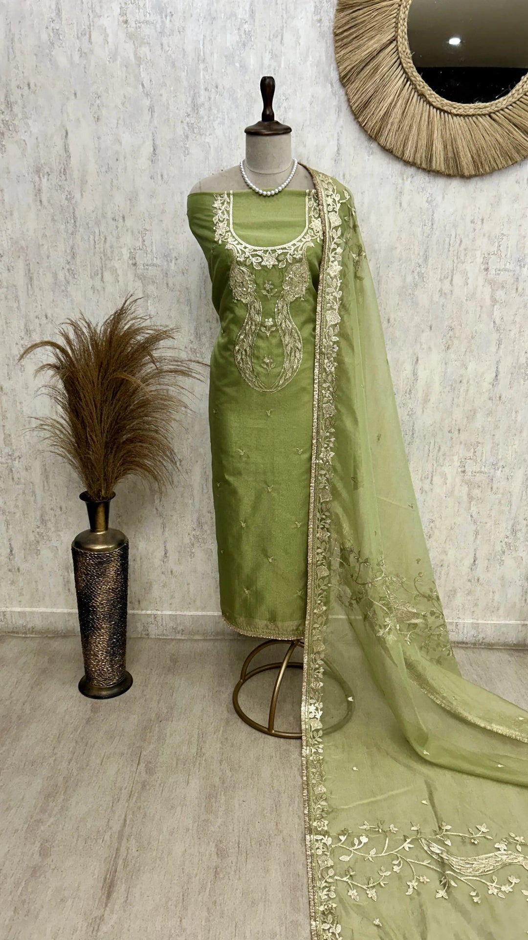 Green embroidered saree on a mannequin against a neutral wall.