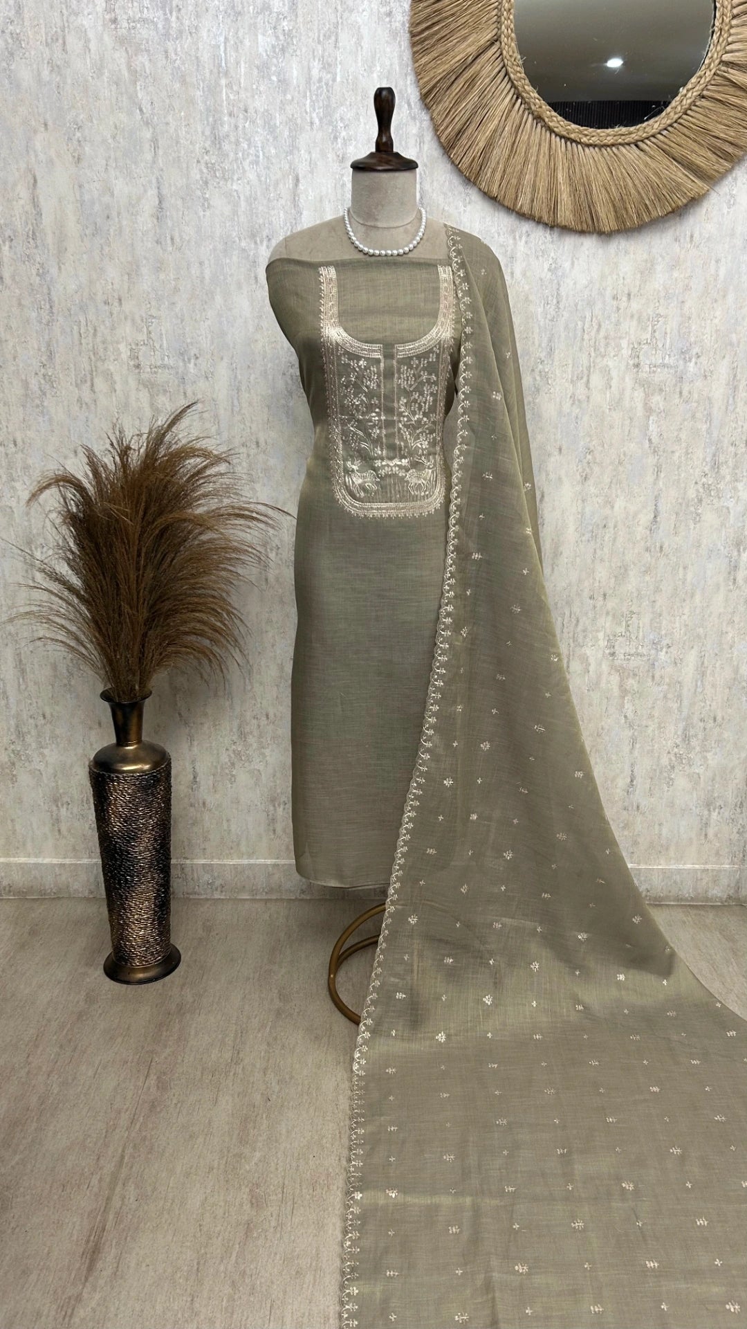 Mannequin wearing a silver embroidered outfit with a sheer dupatta against a neutral background