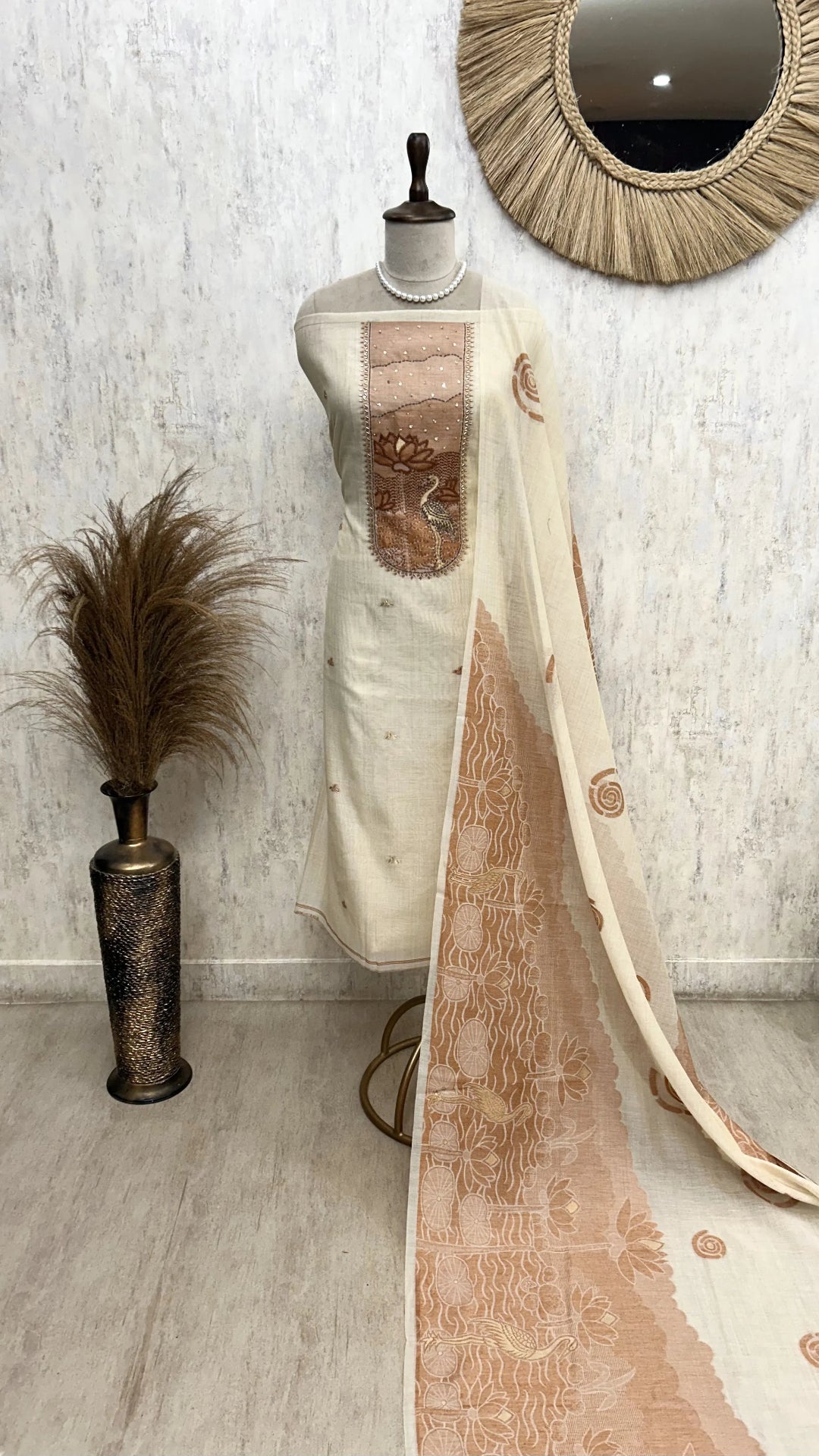 Mannequin with a long, patterned fabric draped over it against a neutral wall.